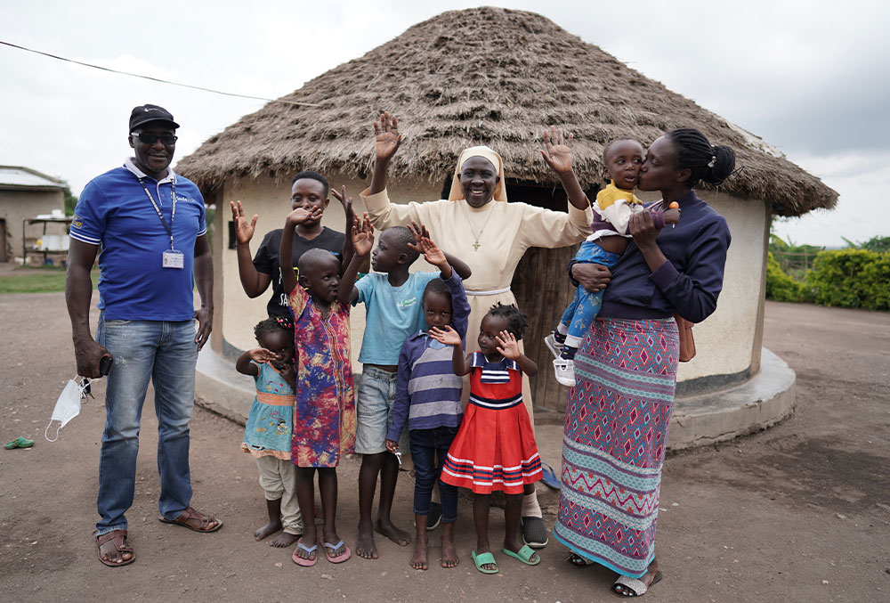 Sister Dr. Liliana Najjuka smiling and raising her hands with Kellen and her son Eric after his cleft surgery