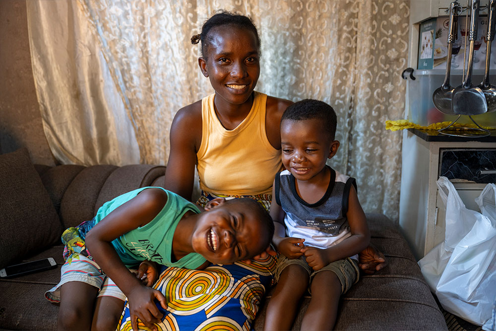 Josephine, Joshua, and Favour smiling for a picture inside their house